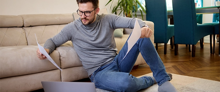 Man sitting on the ground and looking at paperwork