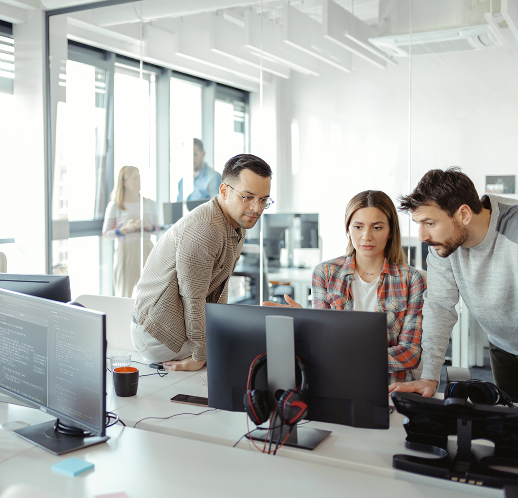 Three people in an office looking at a computer monitor.