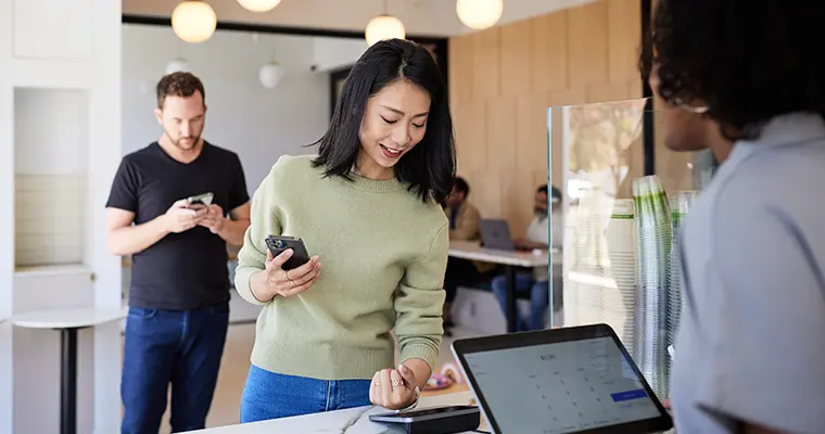 Asian woman at register using watch to pay