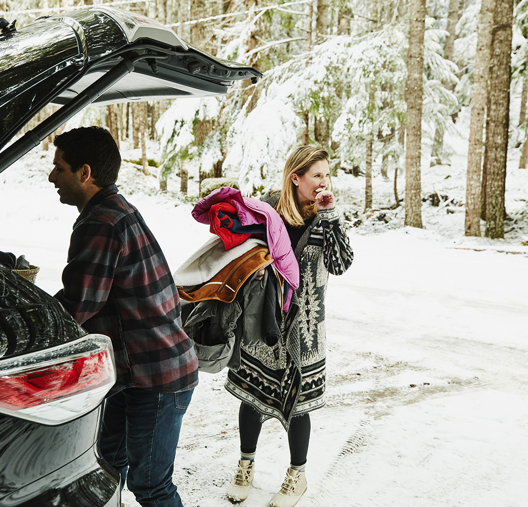 Couple unloading car in the snow for winter vacation