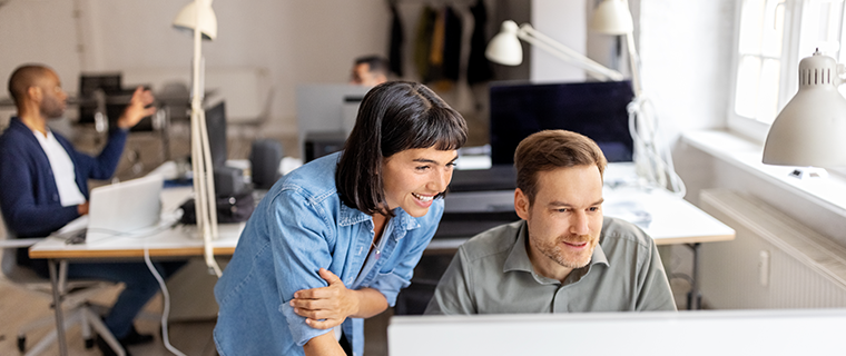 Man at computer with female co-worker looking over his shoulder