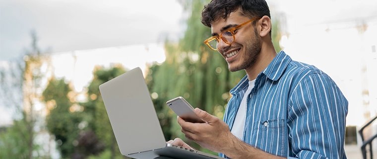 Man looking at his cell phone and laptop